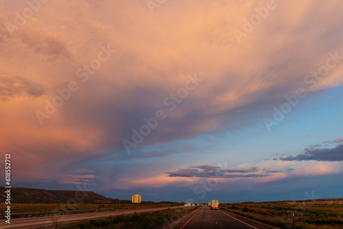 Scenic landscape with highway among mountains and colorful sky at dusk. Blue, orange and purple sky at sunset over the road. Highway 40, Arizona, USA - 06-17-2022