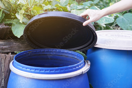 фотографія Closeup hand hold lid to cover water bucket to protect from mosquito to breed inside or other  insects or dust go into water