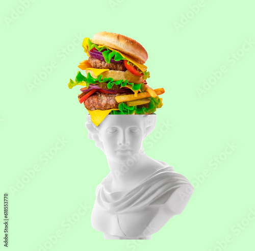 Creative art collage of antique statue head head with huge burger flying out of its head on green background. Fast food and overeating concept. photo