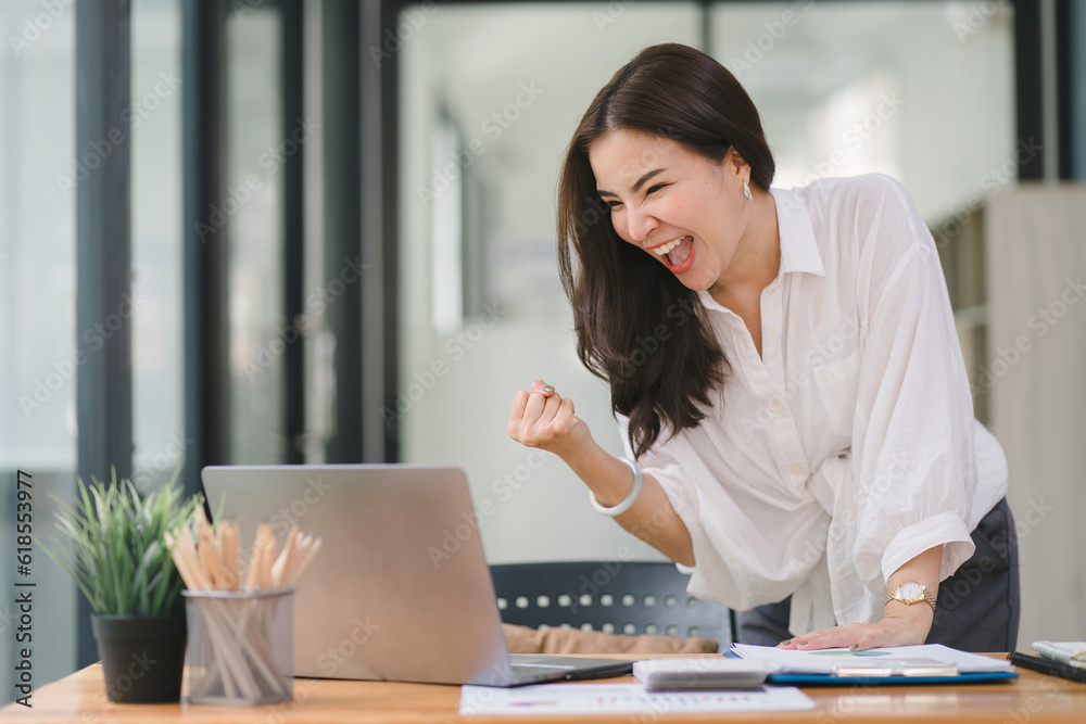Portrait of a happy young businesswoman celebrating success with arms raised in front of a laptop, fists clenched. The freelancer has finished a project. Portrait of a happy young businesswoman celebrating success with arms raised in front of a laptop, fists clenched. The freelancer has finished a project.