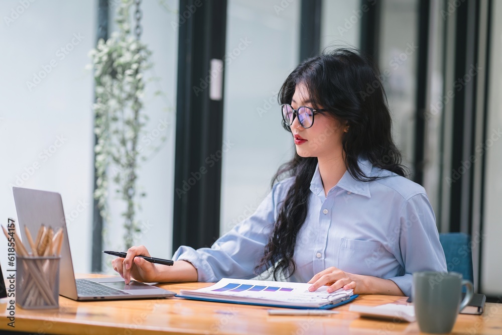 A businesswoman is working at her desk, using a calculator to perform calculations. Finance and accounting concept. A businesswoman is working at her desk, using a calculator to perform calculations. Finance and accounting concept.