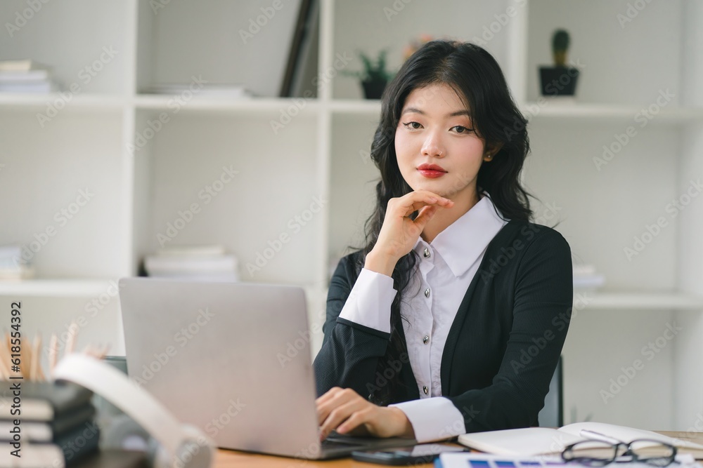 A portrait of a smiling, young, beautiful, professional, and confident millennial Asian businesswoman using a digital tablet to analyze sales data at a modern office. A portrait of a smiling, young, beautiful, professional, and confident millennial Asian businesswoman using a digital tablet to analyze sales data at a modern office.