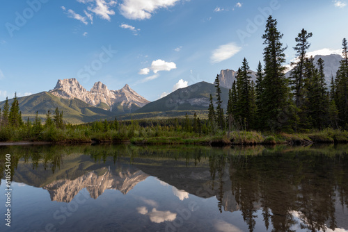 Incredible nature scenery outside of Banff National Park during summer time with iconic Three Sisters in view on sunset, golden hour afternoon. 
