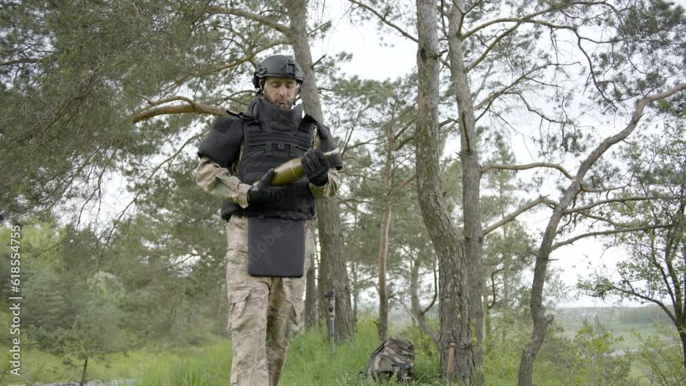 Demining. Sapper carefully carries an anti-tank warhead in his hands in forest and looking forward. Slow motion Demining. Sapper carefully carries an anti-tank warhead in his hands in forest and looking forward. Slow motion