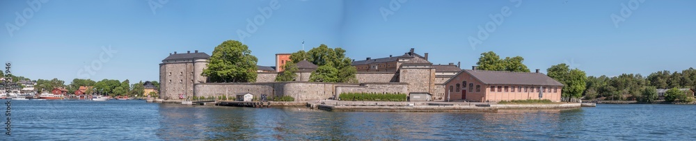 Vaxholm fortress in the archipelago town Vaxholm, pier, hotel and boats, a sunny summer morning in Stockholm,