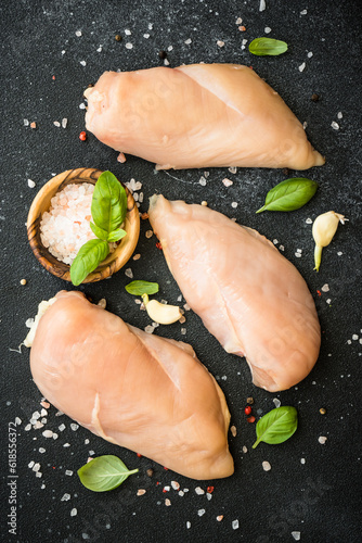 Chicken fillet, raw chicken meat breast with spices at dark background. Top view with space for text.