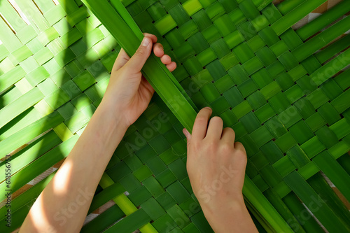 The child weaves cattail leaves. Close-up. DIY children with their own hands. Development of fine motor skills. An idea for children's creativity