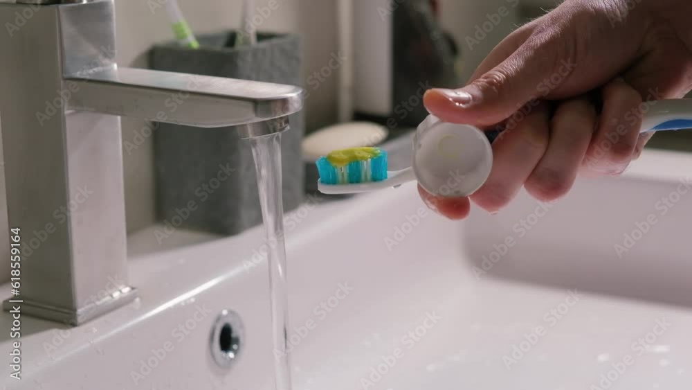 A male eye squeezes toothpaste from a tube onto a brush close-up. A male eye squeezes toothpaste from a tube onto a brush close-up.