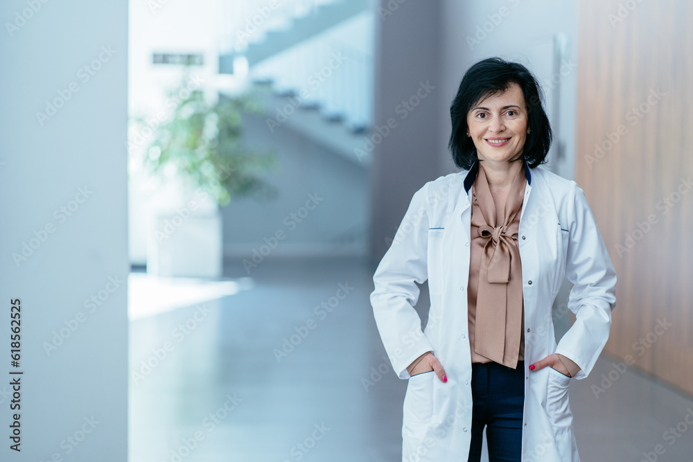 Portrait of positive female doctor psychologist in lab white coat in lobby of in modern hospital clinic office. Medicine, profession and healthcare concept. Portrait of positive female doctor psychologist in lab white coat in lobby of in modern hospital clinic office. Medicine, profession and healthcare concept.