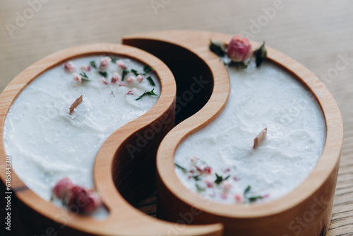 Fototapeta Naklejka Na Ścianę i Meble -  Handmade aroma concept. Soy candle in wooden yin and yang shape and dry flowers scented with natural wax close-up