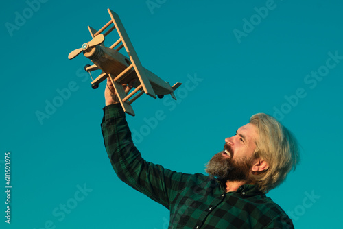 Man dream. Bearded man dreams with plane. Daydreamer. Dreams and imagination. Dreamy father. Bearded man play with toy plane. Funny crazy man with a wooden airplane. Dreams of flying. Travel concept.
