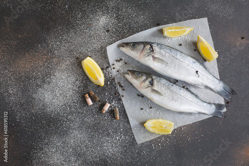 Fresh seabass and ingredients for cooking on a black background.