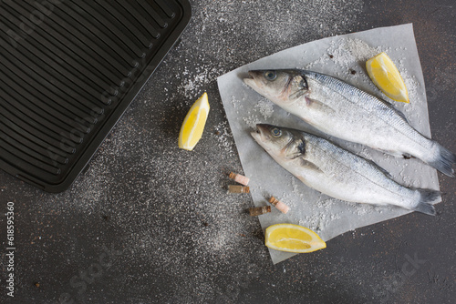 Fresh seabass and ingredients for cooking on a black background.