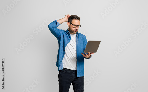 Tableau sur toile Confused disappointed businessman with hand in hair reading e-mail over laptop o