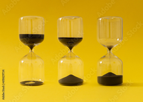 Like sands through the hourglass, so are the days of our lives. Creative hourglass, sandglass, sand timer or sand clock against yellow background concept. Minimal background idea. Hourglass aesthetic.