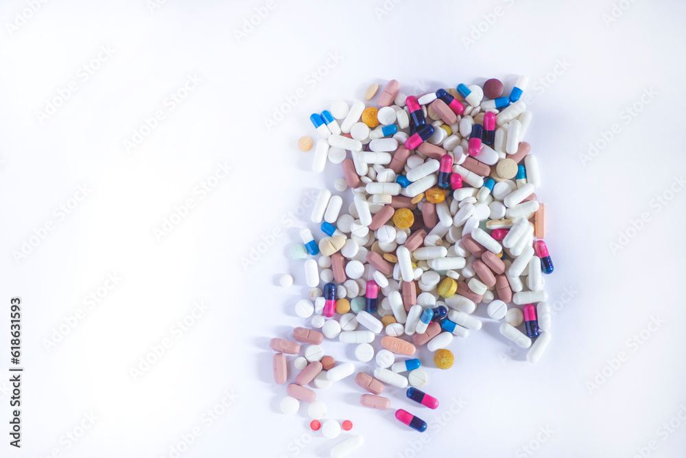 Several old pills of different colors are laid out on a light gray surface. Several old pills of different colors are laid out on a light gray surface.