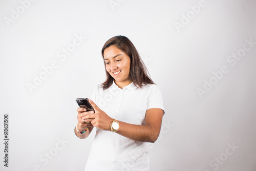 photograph of latina woman using cell phone on a photo studio background. Concept of people and technology.