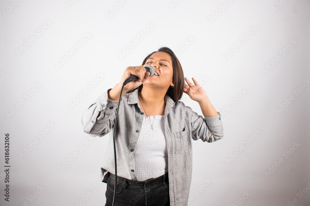 photo of latin woman singing passionately with a microphone on light studio background. Concept of people and hobbies. photo of latin woman singing passionately with a microphone on light studio background. Concept of people and hobbies.