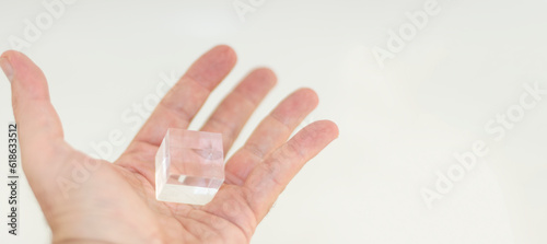 One hand holding a cube of PMMA, acrylic glass, perspex photo