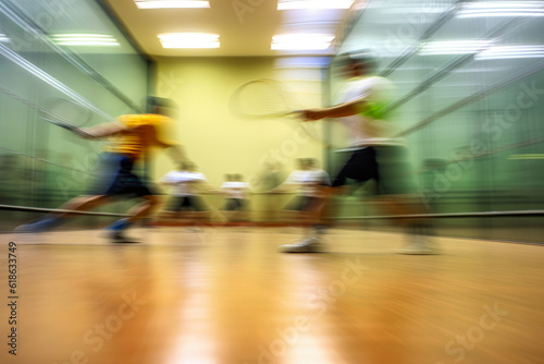 An action-packed scene of a racquetball game, the players moving so fast they're just a blur against the backdrop of the vivid court