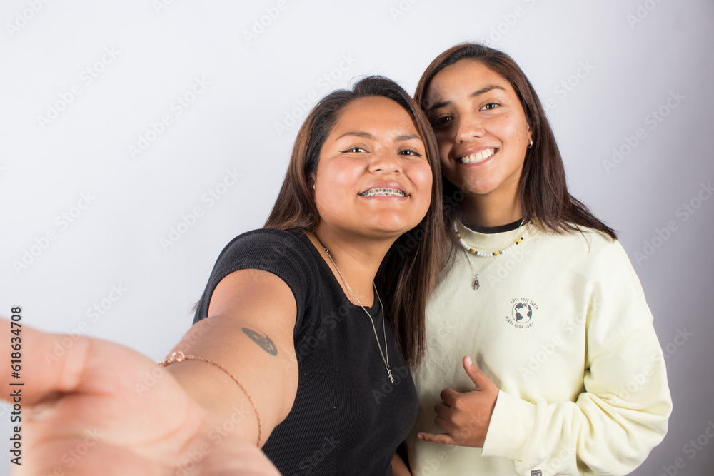 photograph of a female couple taking a selfie on a light studio background. Concept of people and human relationships. photograph of a female couple taking a selfie on a light studio background. Concept of people and human relationships.