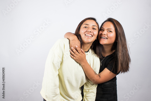Portrait of two young women embracing on a white studio background. Concept of people.