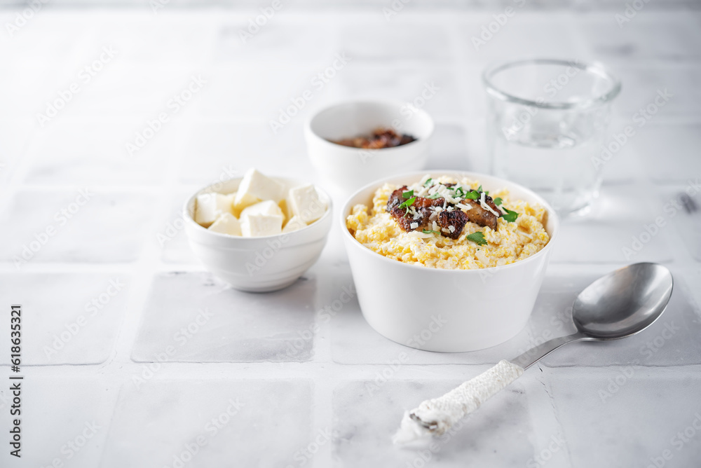 Corn porridge with fried bacon, parsley and Feta cheese in a bowl Corn porridge with fried bacon, parsley and Feta cheese in a bowl