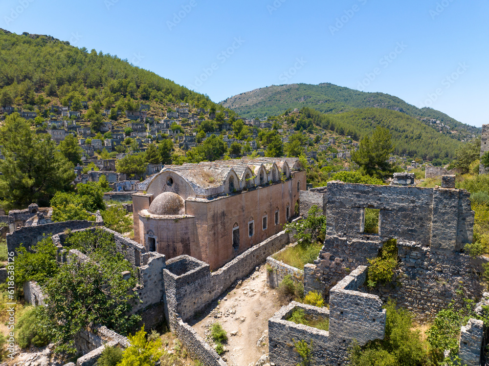 Historical Lycian village of Kayakoy, Fethiye, Mugla, Turkey. Drone aerial shot from above of the Ghost Town Kayakoy. Greek Village. Evening moody warm sun of the ancient city of stone