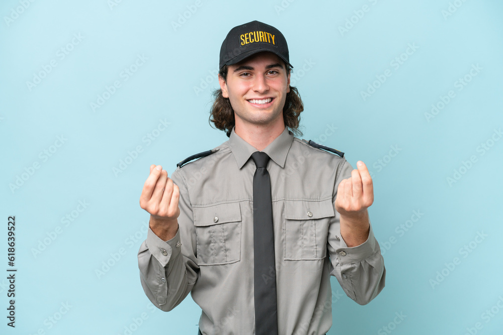 Young safeguard man isolated on blue background making money gesture Young safeguard man isolated on blue background making money gesture