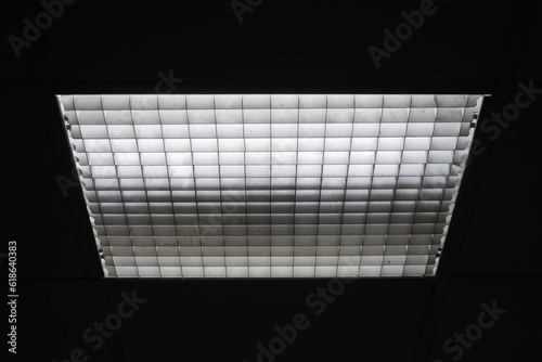 Bilde på lerret Fluorescent lamps in square lampshade with cellular mesh grid in dark room