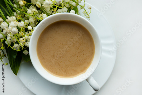 Coffee mug with a bouquet of flowers lily of the valley. View from above  the concept of morning.