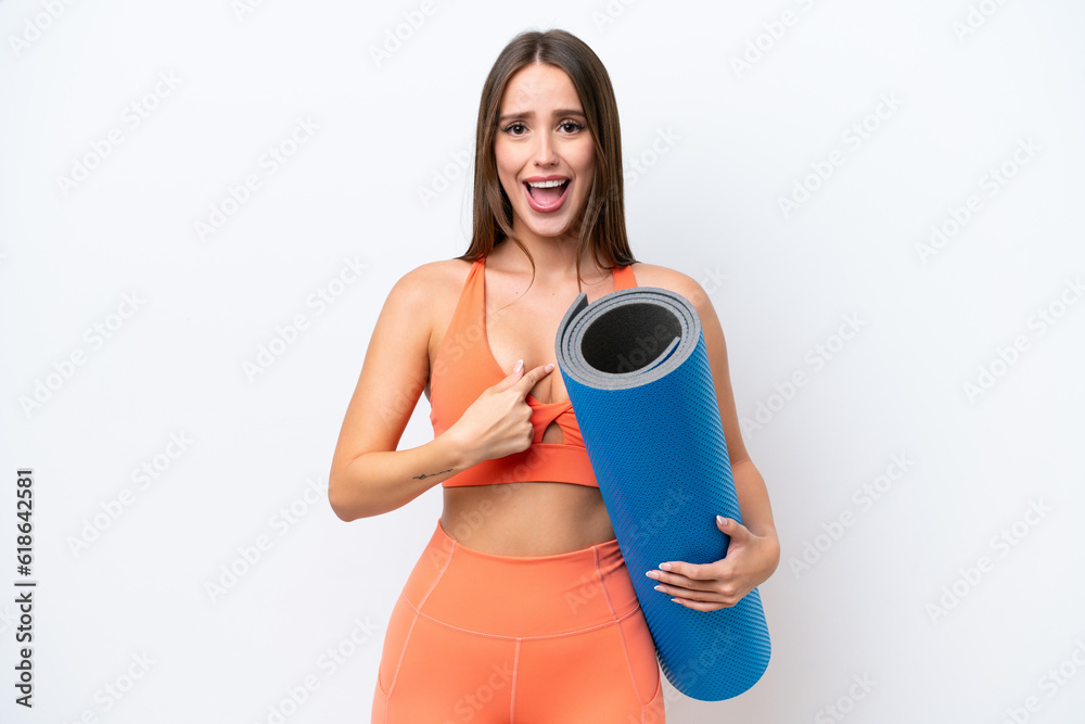 Young beautiful sport woman going to yoga classes while holding a mat isolated on white background with surprise facial expression Young beautiful sport woman going to yoga classes while holding a mat isolated on white background with surprise facial expression