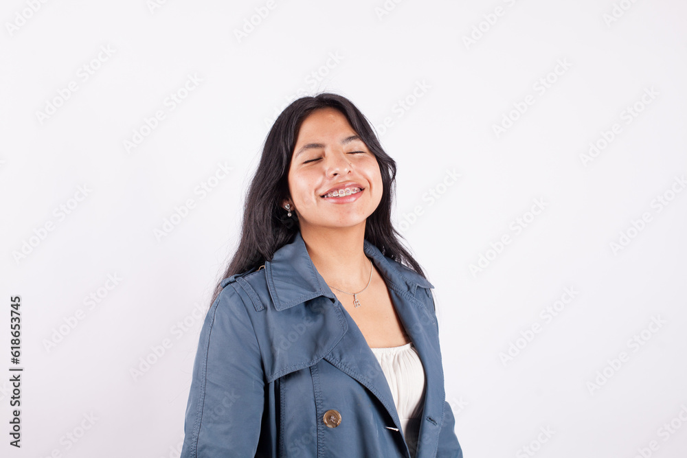 Portrait of latina woman smiling with eyes close on light background of photo studio. Concept of people. Portrait of latina woman smiling with eyes close on light background of photo studio. Concept of people.