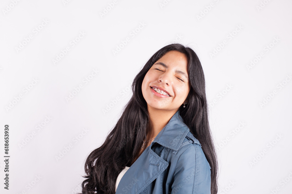 Portrait of latina woman smiling with eyes close on light background of photo studio. Concept of people. Portrait of latina woman smiling with eyes close on light background of photo studio. Concept of people.