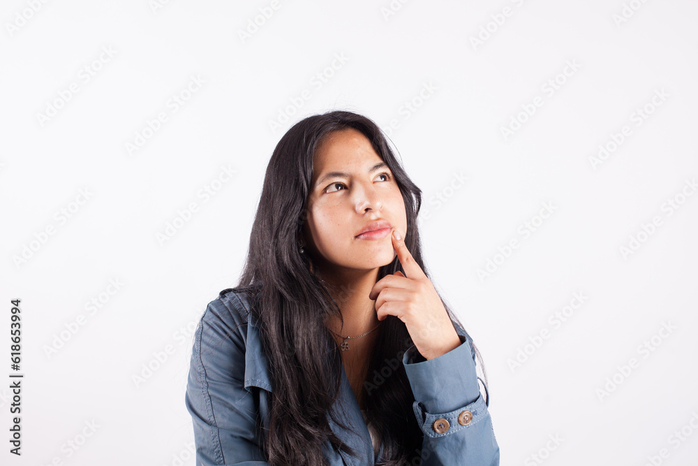Photograph of young woman with thoughtful gesture on white studio background. Concept of people and hobbies. Photograph of young woman with thoughtful gesture on white studio background. Concept of people and hobbies.