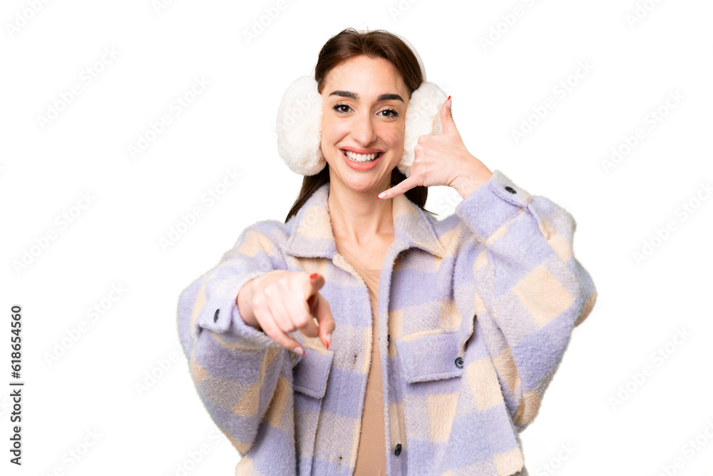 Young caucasian woman wearing winter muffs over isolated chroma key background making phone gesture and pointing front Young caucasian woman wearing winter muffs over isolated chroma key background making phone gesture and pointing front