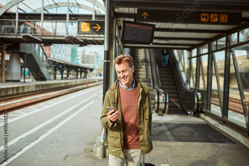 Mature man using a smart phone while waiting for his train at the train station © Geber86