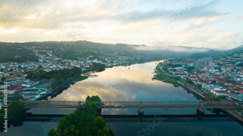 Metal bridge with sky reflection in river water with the light of sunrise. Paraguaçu River in Cachoeira and São Félix Bahia Brazil