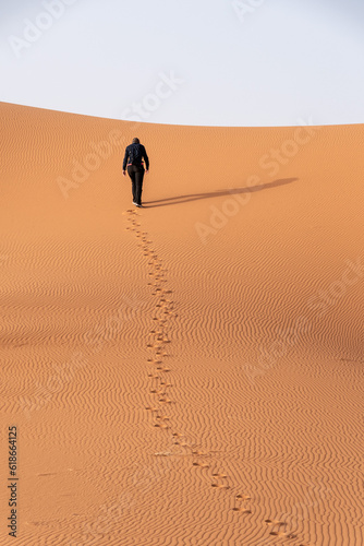 A person walking through the Erg Chebbi desert in the African Sahara