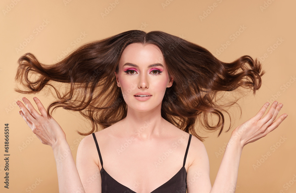 Portrait of beautiful young woman with makeup and gorgeous hair styling on beige background Portrait of beautiful young woman with makeup and gorgeous hair styling on beige background