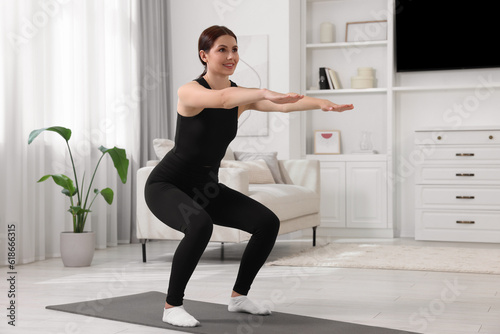 Quadro em tela Morning exercise. Happy woman squatting at home, space for text
