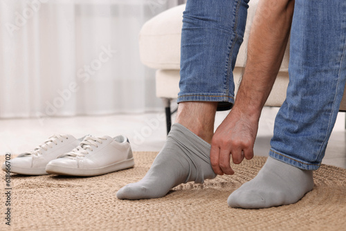 Man putting on grey socks at home, closeup