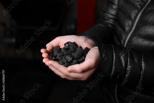 Woman with handful of coal, closeup view