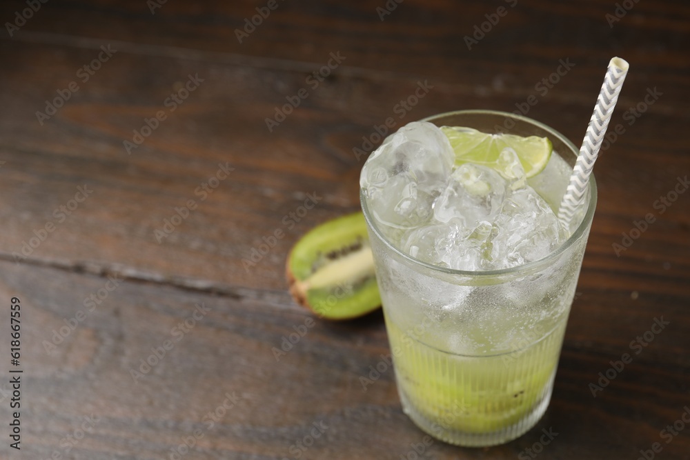 Fototapeta premium Glass of refreshing drink and cut kiwi on wooden table, closeup. Space for text