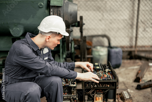 Engineering technicians inspect and assess the reliability of printed circuit assembly boards in manufacturing machine. Identifying errors, impaired, wear then record and report issues to supervisors photo