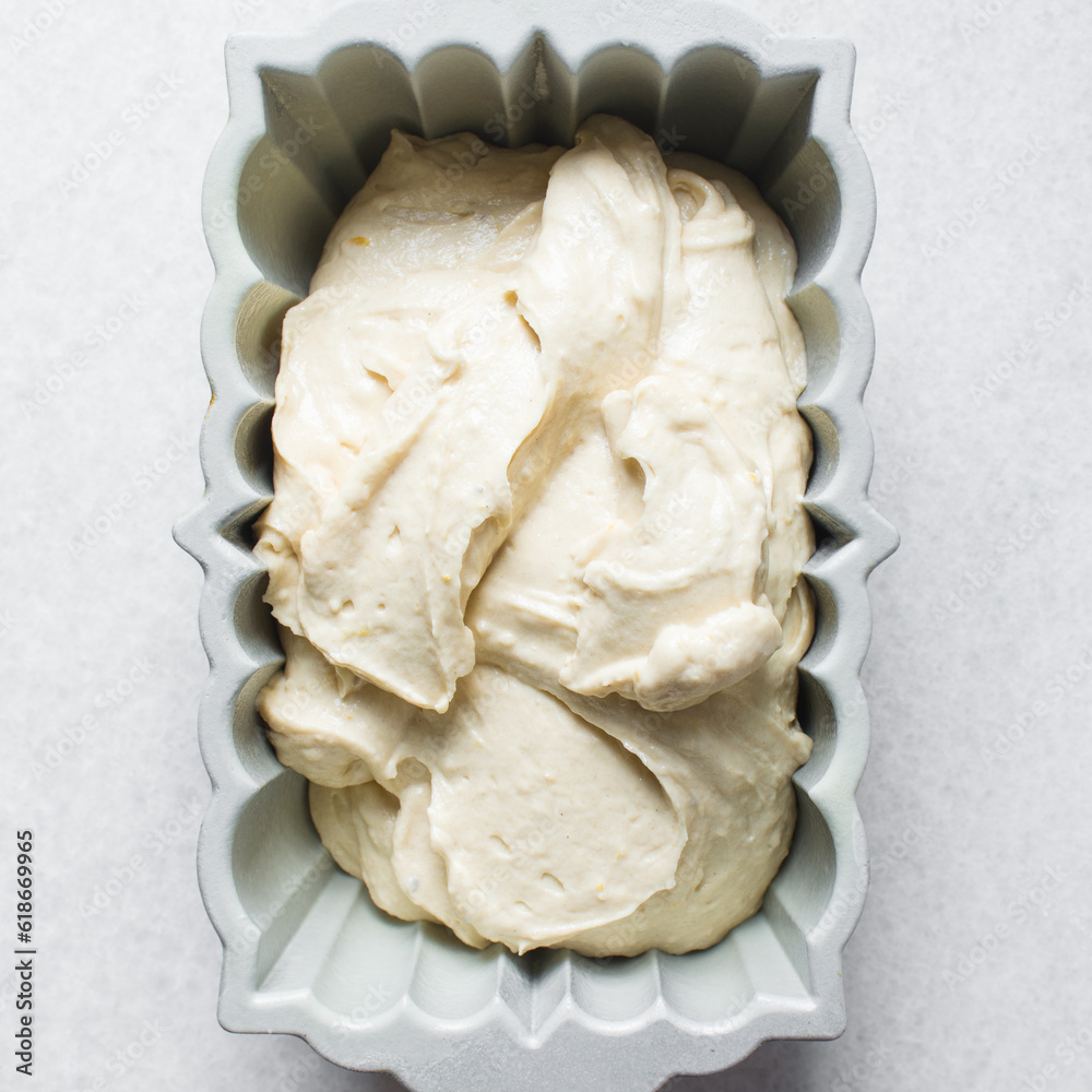Lemon cake batter in a loaf pan, cake batter about to be baked in a silver baking pan, the process of making lemon pound cake Lemon cake batter in a loaf pan, cake batter about to be baked in a silver baking pan, the process of making lemon pound cake