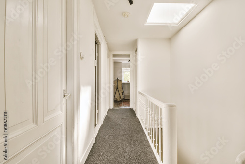 a long hallway with white walls and carpeting on the floor, leading to an open door that leads to another room