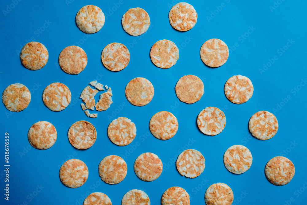 Round rice chips on a blue paper background. Round rice chips on a blue paper background.