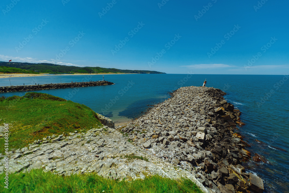Seashore landscape with lighthouse on rocky outcrop on summer sunny day