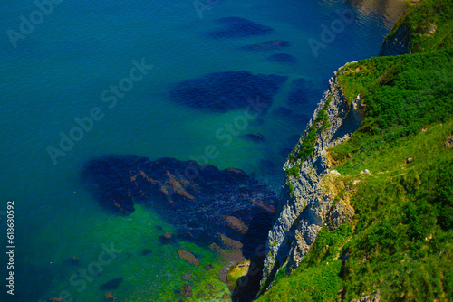 White rocks with green grass by sea on summer sunny day